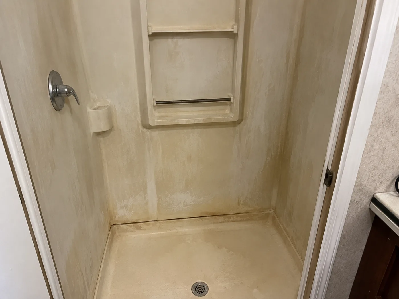 Fiberglass shower before professional glazing refinish — stained and worn