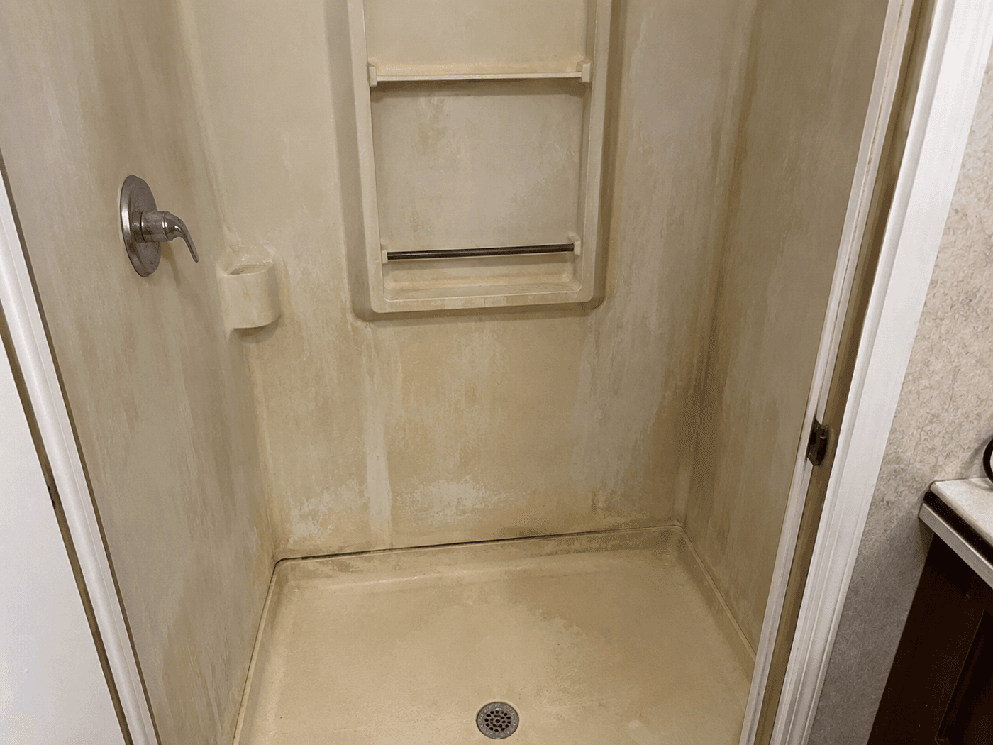 Fiberglass shower before professional glazing refinish — stained and worn